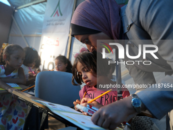 Palestinian children are attending class at a makeshift school in a camp for displaced Palestinians in Deir El-Balah, in the central Gaza St...