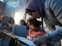 Palestinian children are attending class at a makeshift school in a camp for displaced Palestinians in Deir El-Balah, in the central Gaza St...