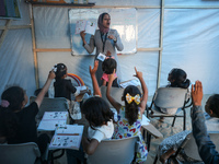 Palestinian children are attending class at a makeshift school in a camp for displaced Palestinians in Deir El-Balah, in the central Gaza St...