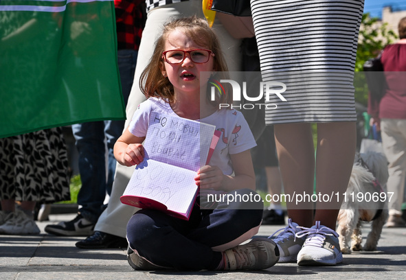 A girl is holding a copybook with a slogan written in it during the FreeAzov action in support of the military held in Russian captivity, at...