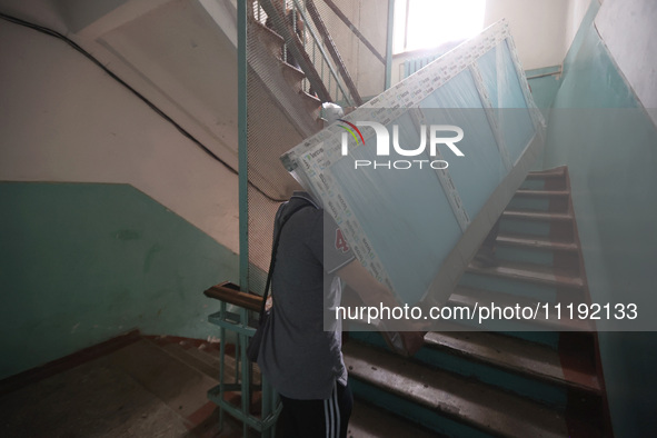 KHARKIV, UKRAINE - APRIL 27, 2024 - Men carry a glass unit up the stairs at Psychiatric Hospital N3 in the Saltivskyi district to replace a...