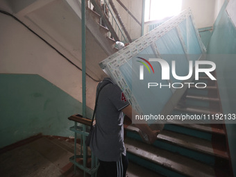 KHARKIV, UKRAINE - APRIL 27, 2024 - Men carry a glass unit up the stairs at Psychiatric Hospital N3 in the Saltivskyi district to replace a...