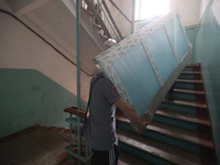 KHARKIV, UKRAINE - APRIL 27, 2024 - Men carry a glass unit up the stairs at Psychiatric Hospital N3 in the Saltivskyi district to replace a...