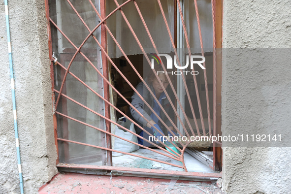 KHARKIV, UKRAINE - APRIL 27, 2024 - A woman collects glass shards on the windowsill at Psychiatric Hospital N3 in the Saltivskyi district fo...