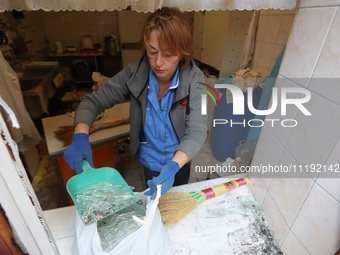 KHARKIV, UKRAINE - APRIL 27, 2024 - A woman collects glass shards on the windowsill at Psychiatric Hospital N3 in the Saltivskyi district fo...