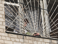 KHARKIV, UKRAINE - APRIL 27, 2024 - A woman collects glass shards on the windowsill at Psychiatric Hospital N3 in the Saltivskyi district fo...