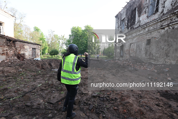 KHARKIV, UKRAINE - APRIL 27, 2024 - A forensic expert of the police films a crater at Psychiatric Hospital N3 in the Saltivskyi district fol...