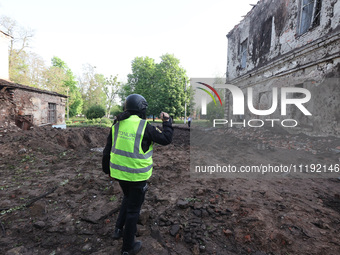 KHARKIV, UKRAINE - APRIL 27, 2024 - A forensic expert of the police films a crater at Psychiatric Hospital N3 in the Saltivskyi district fol...