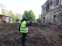 KHARKIV, UKRAINE - APRIL 27, 2024 - A forensic expert of the police films a crater at Psychiatric Hospital N3 in the Saltivskyi district fol...