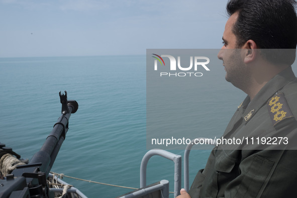 An Islamic Revolutionary Guard Corps (IRGC) Navy military personnel is standing on a warship and monitoring an area during the IRGC marine p...