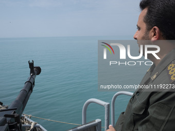 An Islamic Revolutionary Guard Corps (IRGC) Navy military personnel is standing on a warship and monitoring an area during the IRGC marine p...