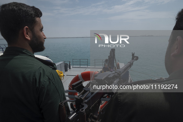 Two Islamic Revolutionary Guard Corps (IRGC) Navy military personnel are standing on a warship and monitoring an area during the IRGC marine...