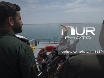 Two Islamic Revolutionary Guard Corps (IRGC) Navy military personnel are standing on a warship and monitoring an area during the IRGC marine...