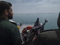 Two Islamic Revolutionary Guard Corps (IRGC) Navy military personnel are standing on a warship and monitoring an area during the IRGC marine...