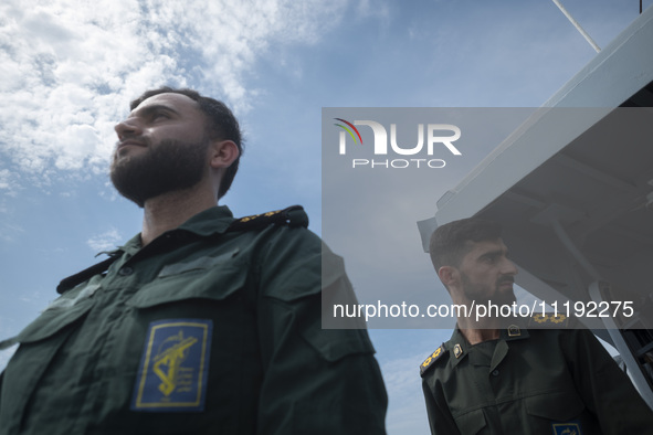 Two Islamic Revolutionary Guard Corps (IRGC) Navy military personnel are standing on a warship and monitoring an area during the IRGC marine...