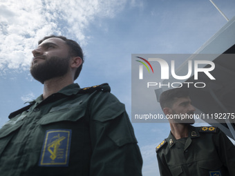 Two Islamic Revolutionary Guard Corps (IRGC) Navy military personnel are standing on a warship and monitoring an area during the IRGC marine...