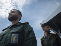 Two Islamic Revolutionary Guard Corps (IRGC) Navy military personnel are standing on a warship and monitoring an area during the IRGC marine...