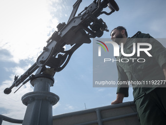 An Islamic Revolutionary Guard Corps (IRGC) Navy military personnel is monitoring an area while standing on a warship during the IRGC marine...