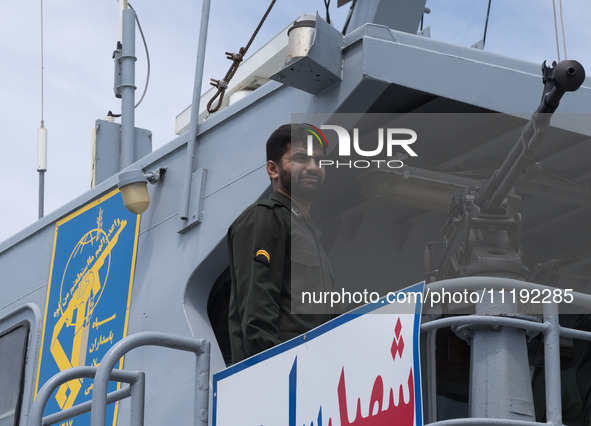 An Islamic Revolutionary Guard Corps (IRGC) Navy military personnel is standing on a warship and monitoring an area during the IRGC marine p...