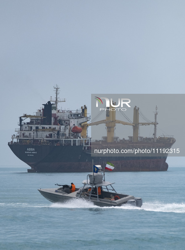 An Islamic Revolutionary Guard Corps (IRGC) speed boat is sailing along the Persian Gulf near a general cargo vessel during the IRGC marine...