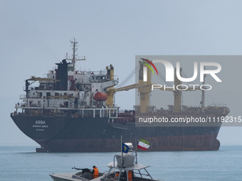 An Islamic Revolutionary Guard Corps (IRGC) speed boat is sailing along the Persian Gulf near a general cargo vessel during the IRGC marine...