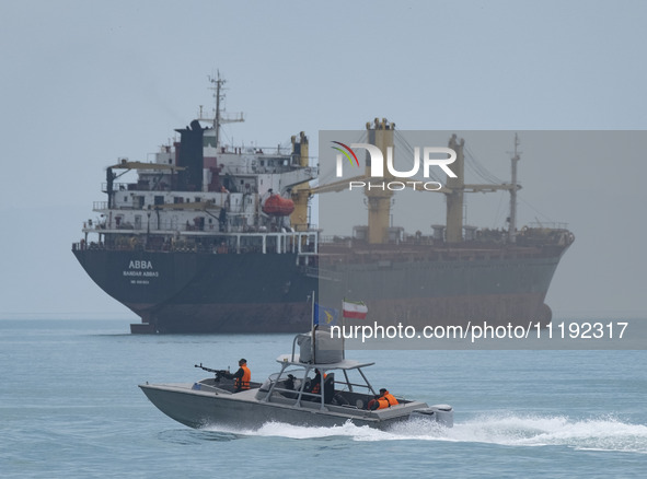 An Islamic Revolutionary Guard Corps (IRGC) speed boat is sailing along the Persian Gulf near a general cargo vessel during the IRGC marine...