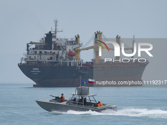 An Islamic Revolutionary Guard Corps (IRGC) speed boat is sailing along the Persian Gulf near a general cargo vessel during the IRGC marine...