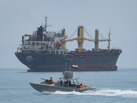 An Islamic Revolutionary Guard Corps (IRGC) speed boat is sailing along the Persian Gulf near a general cargo vessel during the IRGC marine...