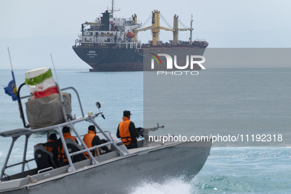 An Islamic Revolutionary Guard Corps (IRGC) speed boat is sailing along the Persian Gulf near a general cargo vessel during the IRGC marine...