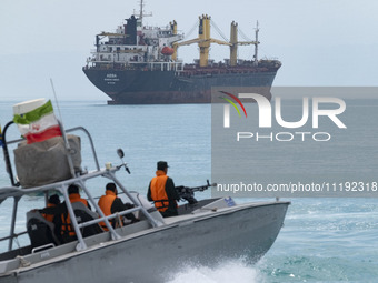 An Islamic Revolutionary Guard Corps (IRGC) speed boat is sailing along the Persian Gulf near a general cargo vessel during the IRGC marine...