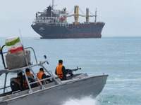 An Islamic Revolutionary Guard Corps (IRGC) speed boat is sailing along the Persian Gulf near a general cargo vessel during the IRGC marine...