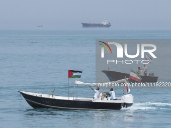 A Basij paramilitary force speedboat is carrying Iranian flags and a Palestinian flag as it sails along the Persian Gulf during the IRGC mar...