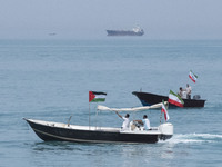 A Basij paramilitary force speedboat is carrying Iranian flags and a Palestinian flag as it sails along the Persian Gulf during the IRGC mar...