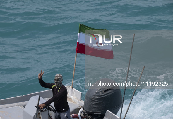 A member of the Basij paramilitary force is sailing along the Persian Gulf and flashing a victory sign during the IRGC marine parade commemo...