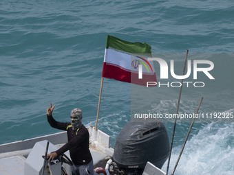 A member of the Basij paramilitary force is sailing along the Persian Gulf and flashing a victory sign during the IRGC marine parade commemo...