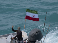 A member of the Basij paramilitary force is sailing along the Persian Gulf and flashing a victory sign during the IRGC marine parade commemo...