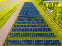 Solar panels on a small solar farm are seen on a field between agricultural produce in a countryside in a village near Sandomierz, Poland on...