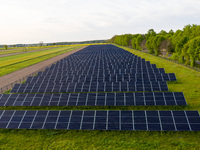 Solar panels on a small solar farm are seen on a field between agricultural produce in a countryside in a village near Sandomierz, Poland on...