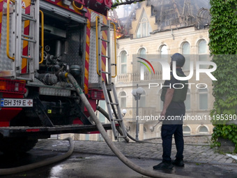 A rescuer is standing by a fire engine outside the Palace of Students of the Odesa Law Academy, which is on fire due to a Russian missile at...