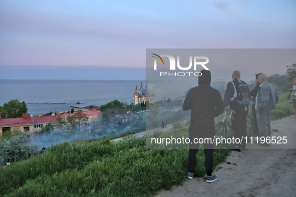 Onlookers are watching the fire at the Palace of Students of the Odesa Law Academy, which was caused by a Russian missile attack in Odesa, U...