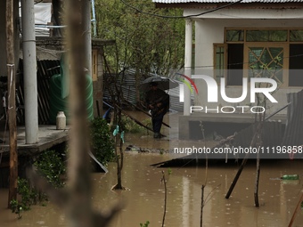 A person is inspecting his house that has been submerged due to flash floods on the outskirts of Sopore, District Baramulla, Jammu and Kashm...