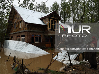 A woman is looking towards her house, which has been submerged, and she had to evacuate due to flash floods on the outskirts of Sopore, Dist...