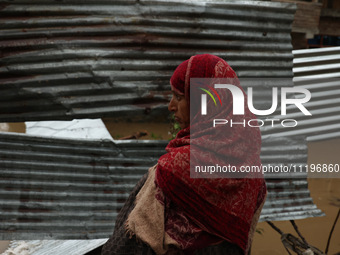 A woman is looking towards her house, which has been submerged, and she had to evacuate due to flash floods on the outskirts of Sopore, Dist...