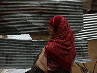 A woman is looking towards her house, which has been submerged, and she had to evacuate due to flash floods on the outskirts of Sopore, Dist...