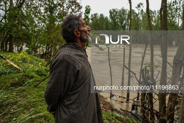 Ghulam Mohammad, 78, is looking towards the river that is causing a flood-like situation outside his house on the outskirts of Sopore, Distr...