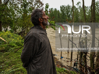 Ghulam Mohammad, 78, is looking towards the river that is causing a flood-like situation outside his house on the outskirts of Sopore, Distr...