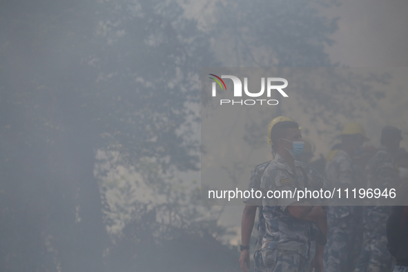 A Nepal Armed Police Force (APF) personnel is wearing a mask as smoke from the forest fire that has been continuing for days envelops a loca...