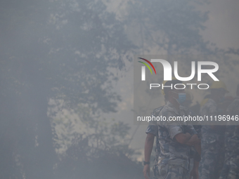 A Nepal Armed Police Force (APF) personnel is wearing a mask as smoke from the forest fire that has been continuing for days envelops a loca...