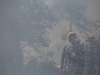 A Nepal Armed Police Force (APF) personnel is wearing a mask as smoke from the forest fire that has been continuing for days envelops a loca...