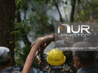 Nepali firefighters from the Nepal Army and Armed Police Force (APF) are holding hoses as they try to control a blaze that started in a loca...